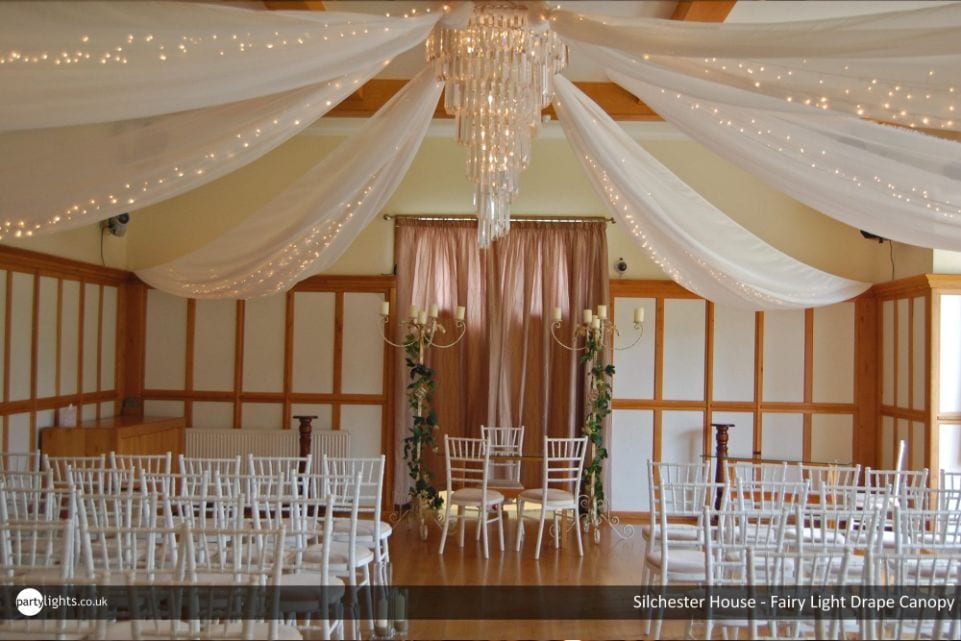 Wedding Decoration Ideas for a Romantically Rustic Day chandelier with fairy lit drapes over a wedding venue with chairs